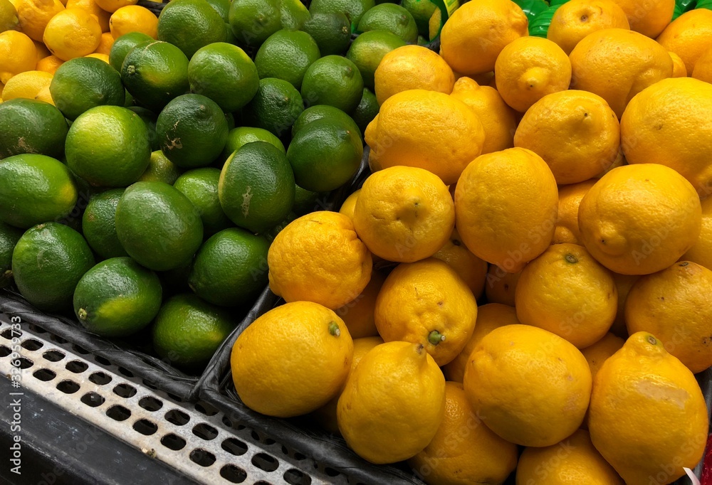 Piles of green lime and lemon fruits at the fresh produce section of a market