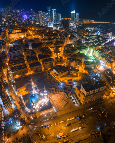 Beirut, Lebanon 2019: Aerial drone shot of Downtown Beirut in foreground showing Mohammad Al Amin Mosque and St. George church with city skyline at night.