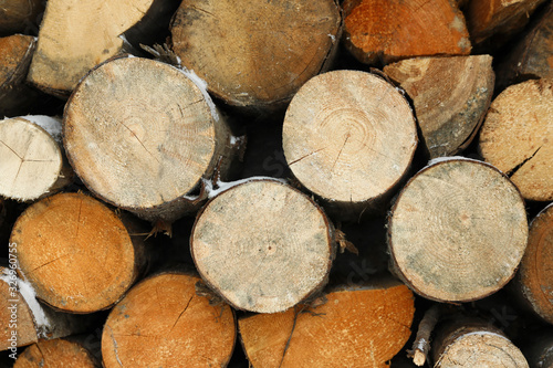 Stacked firewood with snow as background  closeup. Heating house in winter