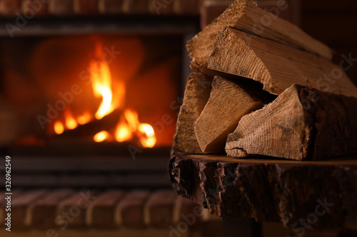 Canvas Print Pile of wood and blurred fireplace on background, space for text