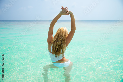Young woman standing in the ocean and posing