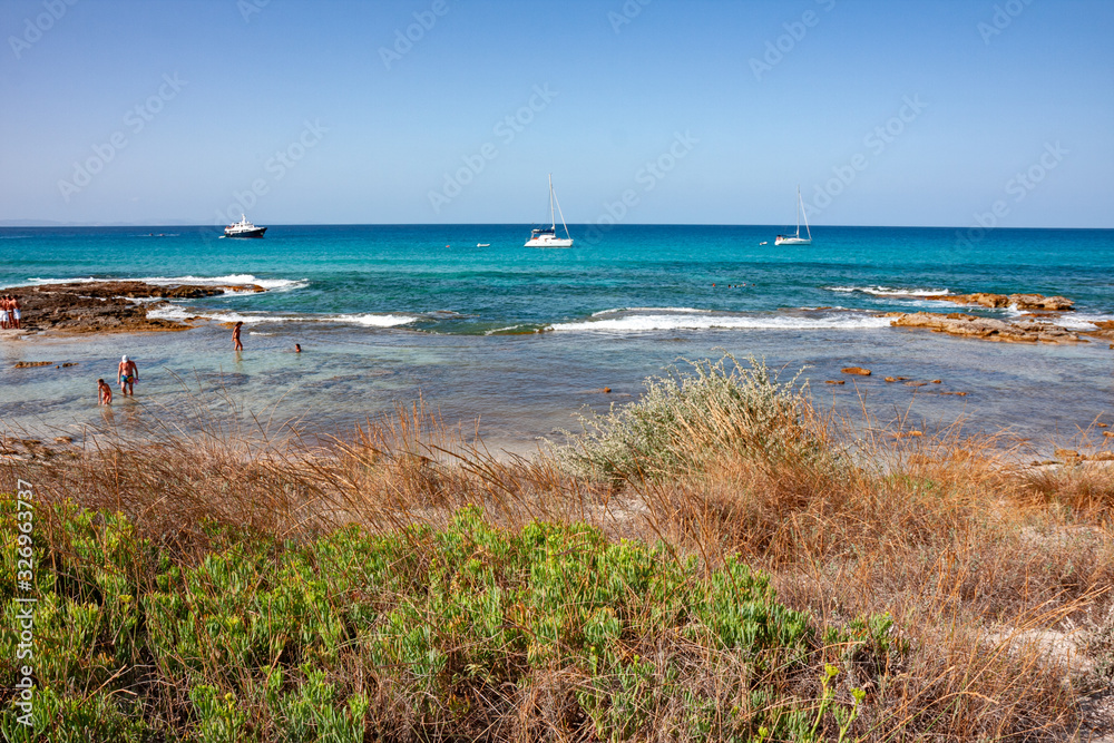Bathers sunbathing in the wild and sunny bays of Formentera in the Balearic islands of Spain.
