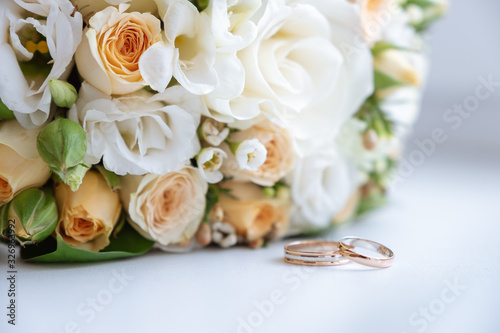 wedding rings lie in front of the wedding bouquet on a white table. close up