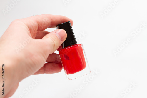 a bottle of red nail polish in hand