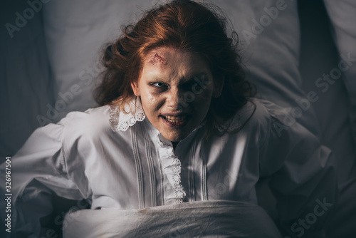 top view of paranormal girl in nightgown lying in bed