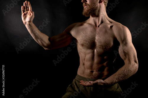 Beautiful muscles, athletic body. Studio photography on a black background, naughty light. Combat sport. Fair-haired sports man