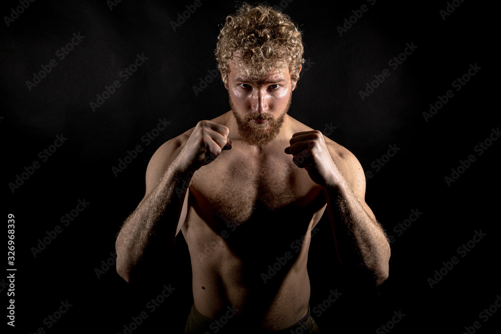 Fototapeta premium Beautiful muscles, athletic body. Studio photography on a black background, naughty light. Combat sport. Fair-haired sports man