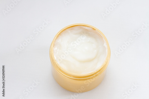 close up of a white cream in a container on white background