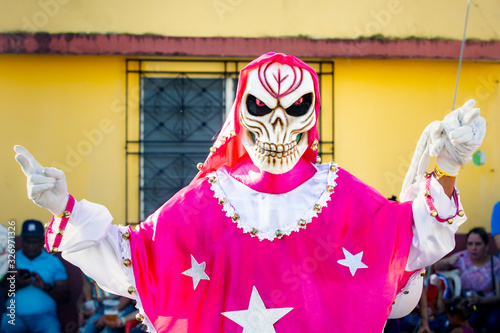 human in flamboyant costume poses for photo on city street at dominican carnival