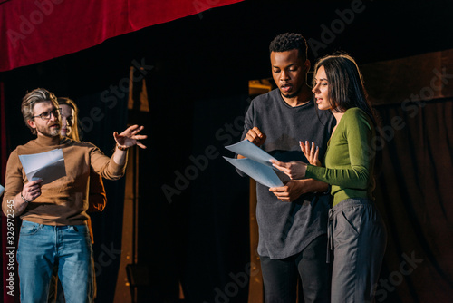 Foto theater director, multicultural actors and actress rehearsing on stage