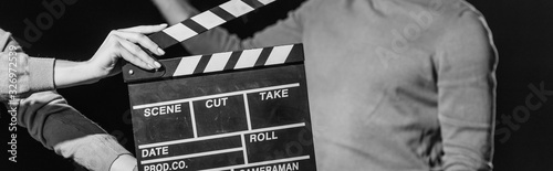 panoramic shot of actor with clapboard in front, isolated on black, black and white