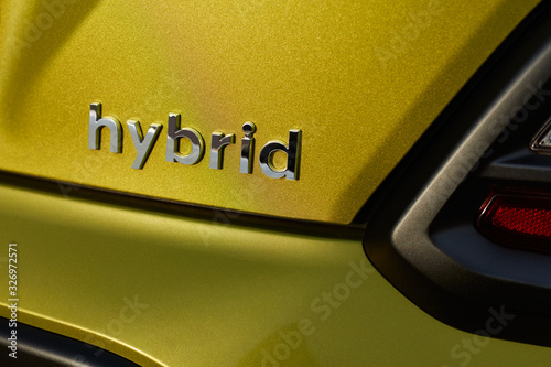 Chromed hybrid car logo on green background photo