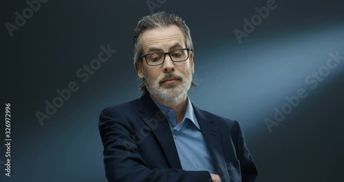 Portrait of rich handsome businessman of middle-age in glasses and suit taking out money from pocket and proposing. Financial successful man in business style giving dollars to camera like offering. photo