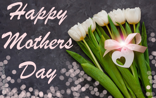 Fototapeta Naklejka Na Ścianę i Meble -  Heppy Mothers Day card message sign. White tulip flowers and black gift box on dark background with bokeh lights flat lay