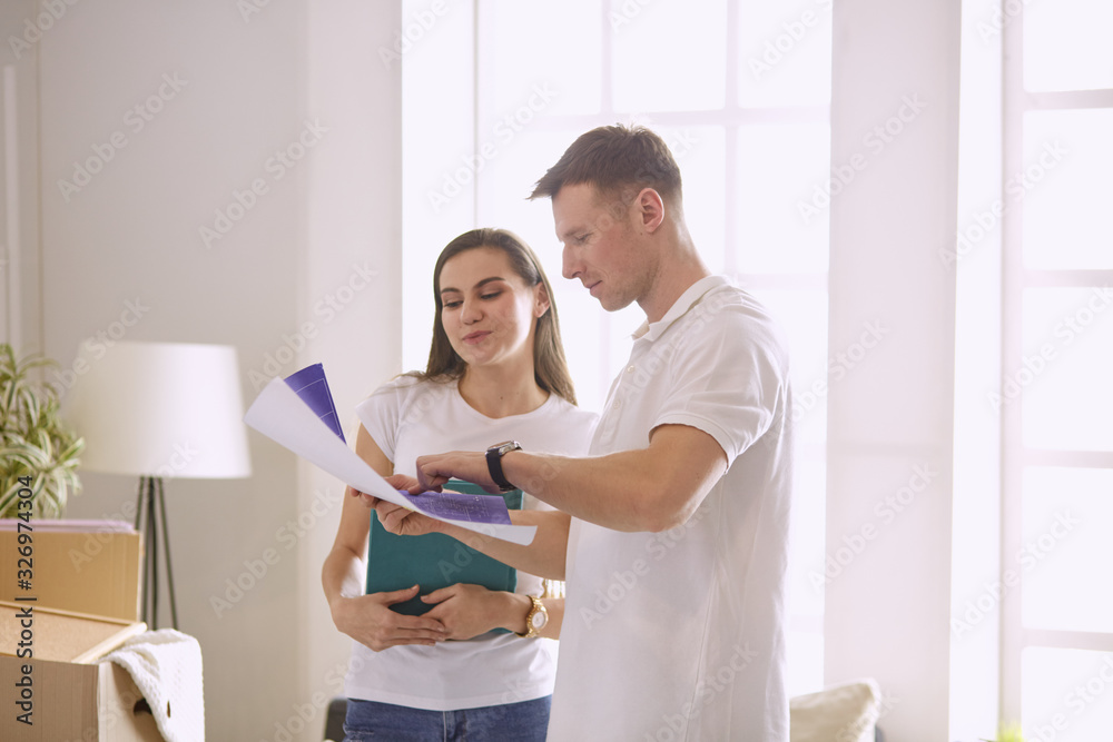 Fototapeta premium Young Hispanic couple looking at blueprints of new home, high angle view