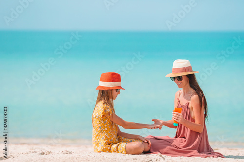 Young mother applying sun cream to daughter nose on the beach. Sun protection