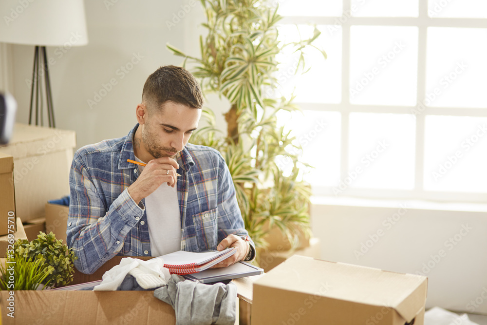 Handsome man with boxes in the new apartment after moving Handsome man with boxes in the new apartment after moving