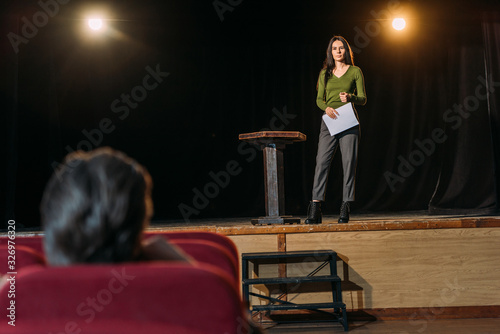 selective focus of theater director and beautiful actress with screenplay on stage