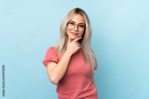 Teenager girl over isolated blue background with glasses and smiling