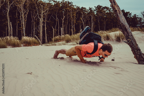 Outdoor Adventure. Traveler with backpack do push ups. Man has fun journey. Freedom travel. Backpacker holiday. Active healthy lifestyle concept. Poland Europe vacation. Copy space. Hiking desert.
