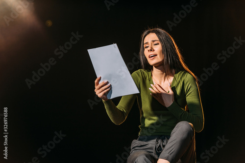 attractive emotional actress reading scenario on black