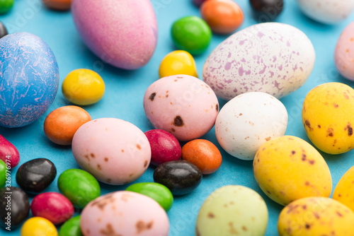 Selective focus of bright colorful sweets and easter eggs on blue background