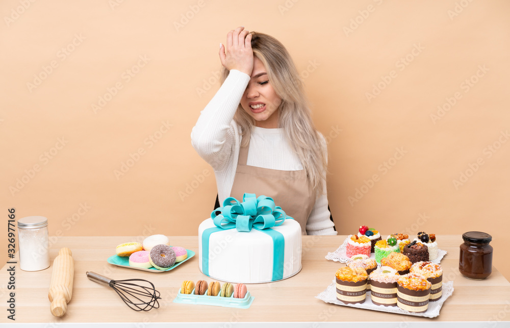 Teenager pastry chef with a big cake in a table having doubts with confuse face expression Teenager pastry chef with a big cake in a table having doubts with confuse face expression