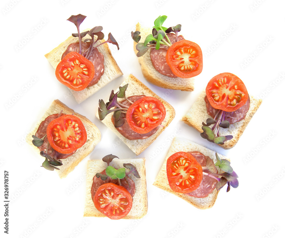 Small sandwiches, finger food, with sliced salami, tomatoes and micro greens radish isolated on white background. Pieces of bread with sausage and vegetables top view.. Small sandwiches, finger food, with sliced salami, tomatoes and micro greens radish isolated on white background. Pieces of bread with sausage and vegetables top view..
