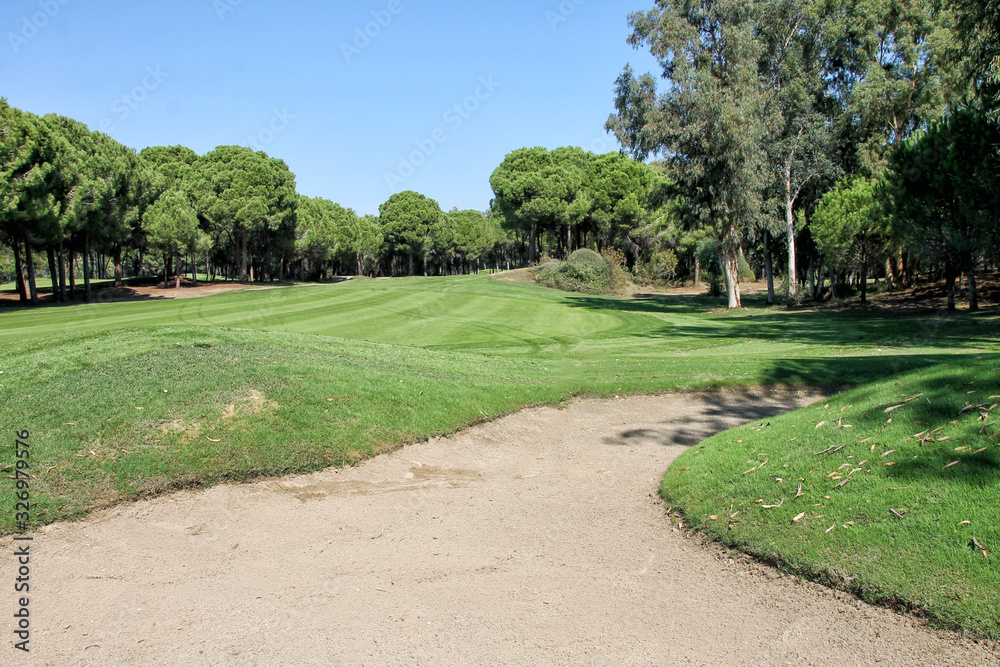 A large Golf course with a perfectly manicured lawn. Sand pit on the Golf course.