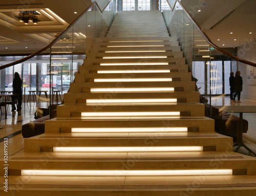 wooden staircase with illuminated steps and glass railing