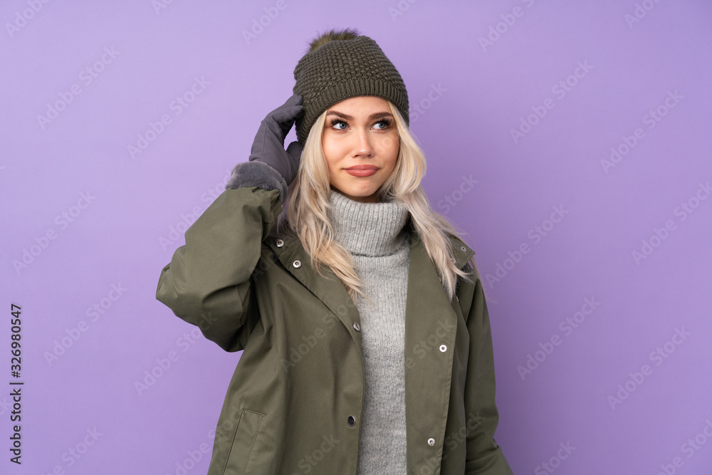 Teenager blonde girl with winter hat over isolated purple background having doubts Teenager blonde girl with winter hat over isolated purple background having doubts