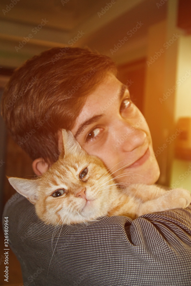 Teen guy hugs a cat. Holds the animal in his arms. Portrait. The concept of friendship of man and animal. Allergy to wool.