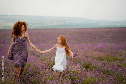 Woman and girl with red hair in lavender field in rainy day