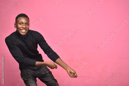 Φωτογραφία young black man posing like he's pulling something along