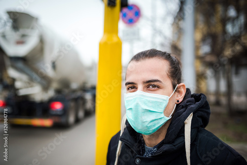 Young man wearing a medical face mask at the street. Air pollution concept. Coronavirus protection concept.