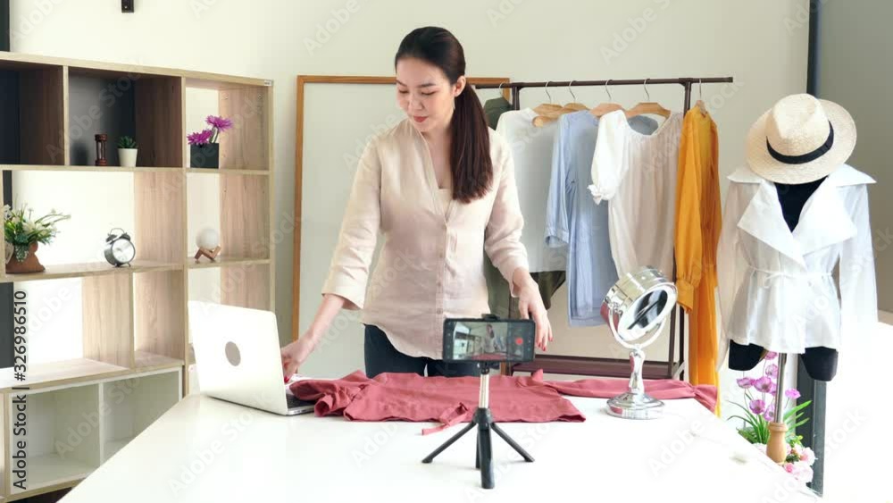 4k video of Attractive young fashion vlogger sitting in front of camera recording video about fashion and clothing at showroom.
