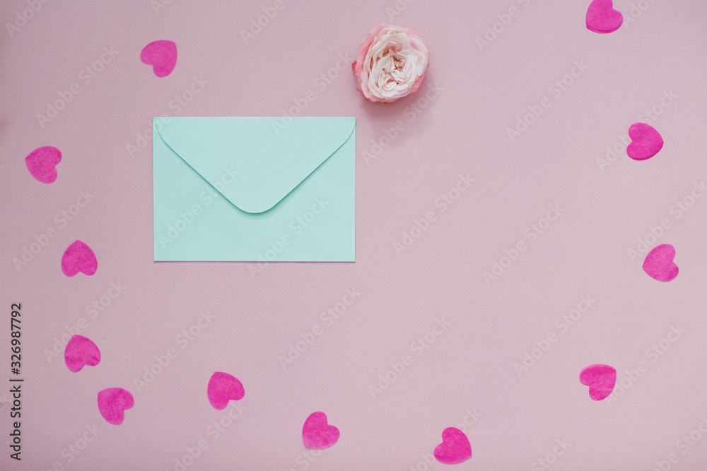 Mint envelope with a pink rose flower and heart shaped confetti