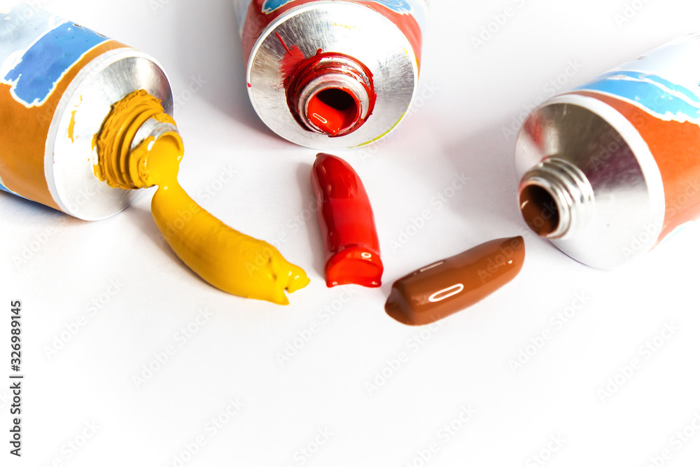 Acrylic paints open tubes.Extruded paints on white paper surface