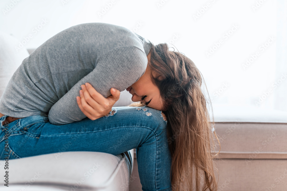 Young woman sitting on the bed with hard stomach pain Young woman sitting on the bed with hard stomach pain