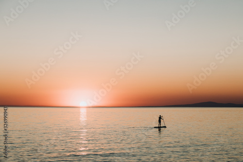 Fototapeta Naklejka Na Ścianę i Meble -  Woman paddling on a board on the sea in sunset