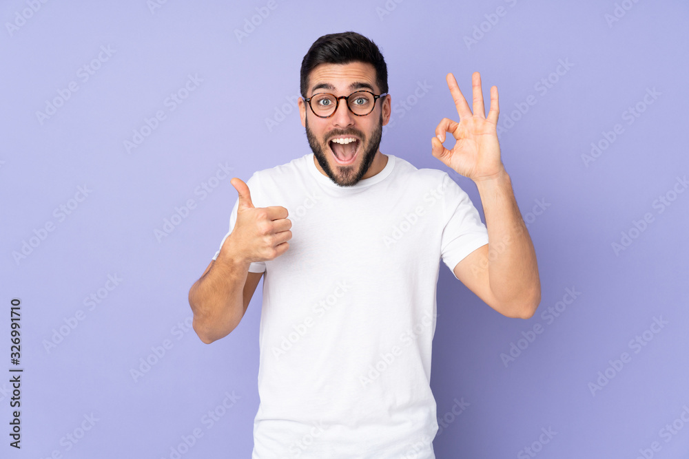 Caucasian handsome man over isolated background showing ok sign and thumb up gesture - obrazy, fototapety, plakaty 