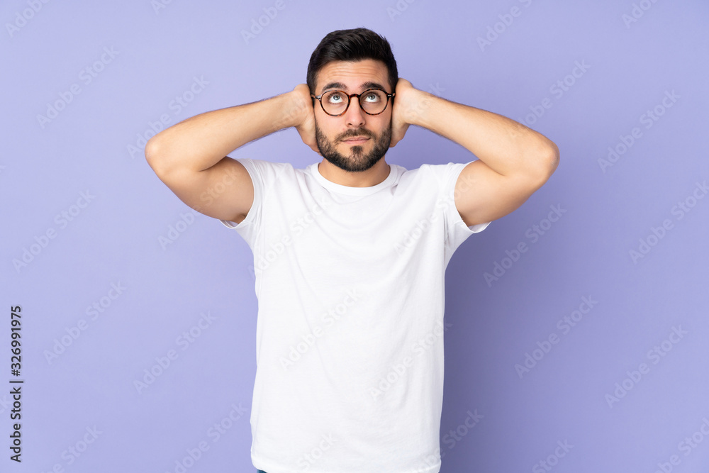 Naklejka premium Caucasian handsome man over isolated background frustrated and covering ears