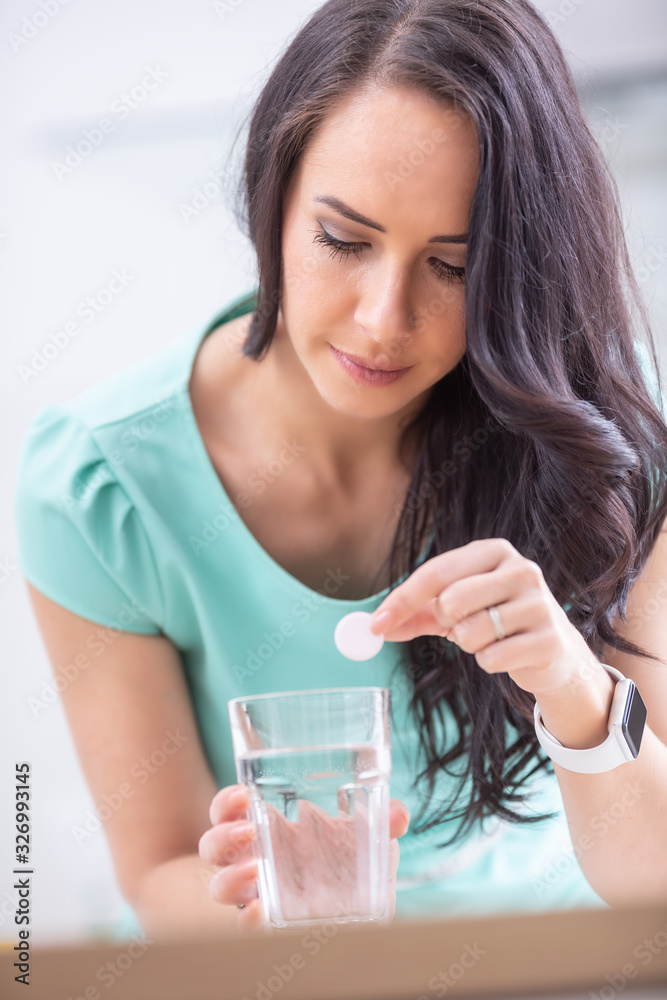 Young woman with magnesia effervescent tablet and glass of pure or mineral water Young woman with magnesia effervescent tablet and glass of pure or mineral water