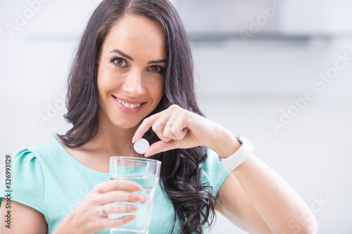 Young woman with magnesia effervescent tablet and glass of pure or mineral water