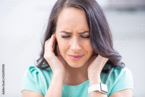 Young woman have headache migraine stress or tinnitus - noise whistling in her ears photo