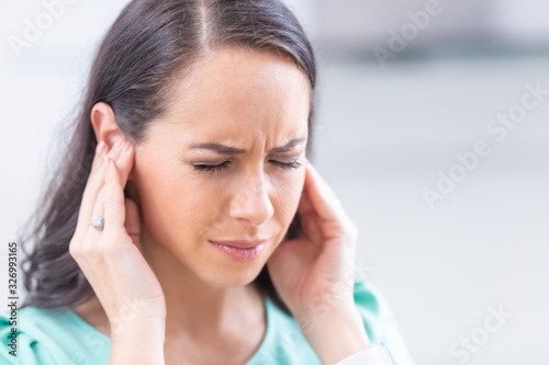 Young woman have headache migraine stress or tinnitus - noise whistling in her ears photo