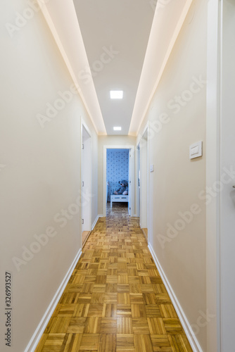 Interior of a bright long doorway corridor with parquet floor