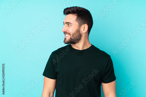 Caucasian handsome man isolated on blue background looking side