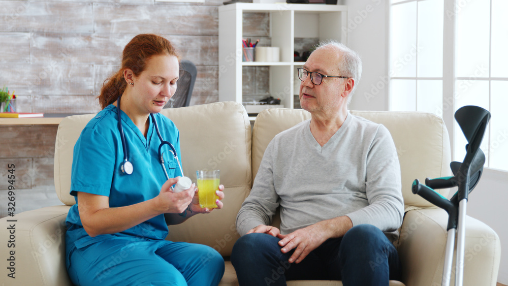 Obraz premium In retirement home nurse is giving daily pills to old man