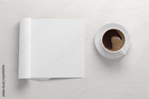 Blank square right magazine page. Workspace with folded magazine mock up on white desk with cup of coffee. View above. 3d illustration